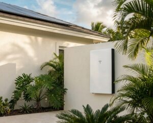 Tesla Powerwall 3 instalada en una residencia moderna con arquitectura caribeña y paneles solares, rodeada de vegetación tropical.